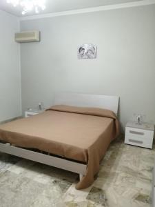 uma cama num quarto branco com duas mesas de cabeceira e duas mesas em Case marino em Termini Imerese
