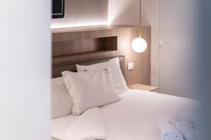 a white bed with white pillows in a bedroom at Sicilia's Art Hotel & Spa in Acitrezza
