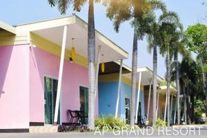 北碧的住宿－AP Grand Resort，一座粉红色的房子,前面有棕榈树
