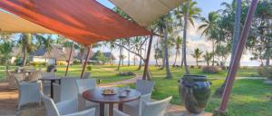 a patio with tables and chairs and palm trees at Bluebay Beach Resort & Spa in Kiwengwa