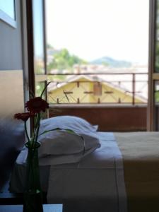 Balcone sul Metauro في Peglio: مزهرية مع وردة على طاولة بجوار سرير
