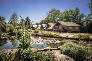a row of luxury tents in a park with a pond at Vakantiepark de Luttenberg in Luttenberg
