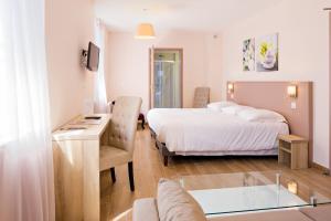 a hotel room with a bed and a desk and a tub at Hôtel du Parc in Le Mont-Dore