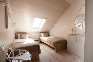 een zolderslaapkamer met twee bedden en een raam bij Domki Amber House in Dźwirzyno
