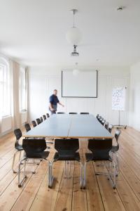 a man standing in a room with a table and chairs at Jugendgästehaus des CVJM Berlin-Kaulsdorf in Berlin