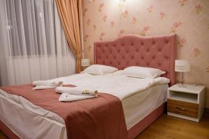 a bed with a pink headboard and two towels on it at Sweet Homes 6 Apartments in Sunny Beach