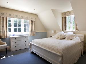 a bedroom with a bed and two windows at The Dower House Hotel in Woodhall Spa