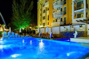 a pool in front of a hotel at night at Sweet Homes Apartments in Sunny Beach