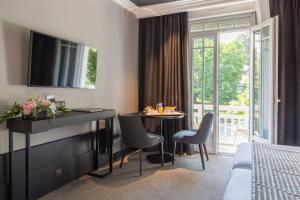 a hotel room with a table and chairs and a bedroom at Golf Hôtel in Brides-les-Bains