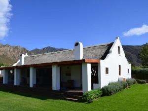 a white house with mountains in the background at Alpaca Inn in Montagu
