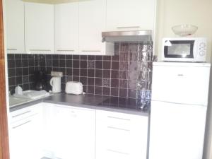 a kitchen with white cabinets and a microwave at Le Haut-Val Résidences in Bellême