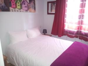 Le Haut-Val Résidences في بيليم: غرفة نوم بسرير أبيض مع بطانية أرجوانية