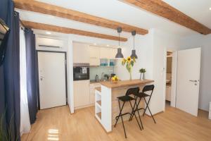 une cuisine avec des placards blancs et des tabourets noirs dans l'établissement Apartment 63 - 3, à Zagreb