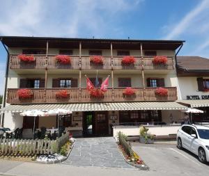 un edificio con un balcón con flores rojas. en Hôtel Restaurant le Gruyérien, en Morlon
