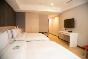 a hotel room with two beds and a television at HATAGO+ THE ALLEY in Taipei
