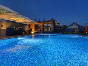 - une grande piscine bleue la nuit dans l'établissement Madison Village, à Kisvárda
