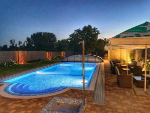 a swimming pool in a backyard with an umbrella at Madison Village in Kisvárda