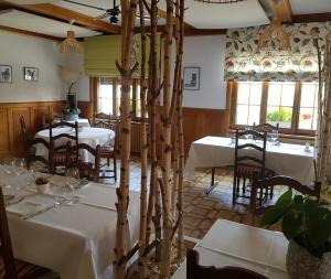 ein Esszimmer mit Tischen, Stühlen und Fenstern in der Unterkunft Hôtel Restaurant le Gruyérien in Morlon