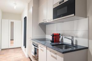 eine Küche mit einer Spüle und einer Mikrowelle in der Unterkunft HITrental Wiedikon Apartments in Zürich
