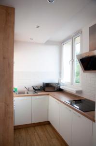 Una cocina con gabinetes blancos y un fregadero y una ventana. en Apartament Jawa, en Łódź