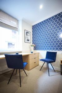 two chairs and a desk in a room with blue tiles at Apartamenty Klasztorna 25 in Poznań