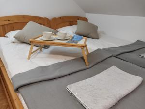 Una cama con una bandeja con dos tazas y una mesa. en Apartma med vinogradi, en Lendava