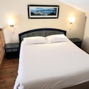 ein Schlafzimmer mit einem großen weißen Bett mit zwei Tischen in der Unterkunft Residence Le Suffren in Grimaud
