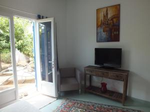 Habitación con TV, silla y puerta. en casa turchina chambre avec piscine privée en Porto Vecchio