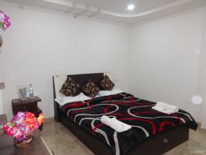 ein Schlafzimmer mit einem Bett mit einer schwarzen und roten Decke in der Unterkunft Indira Villa - 3BHK Getaway near WaterFalls in Mahabaleshwar