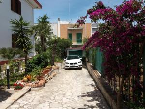 ein weißes Auto, das neben einem Gebäude mit Blumen parkt in der Unterkunft Residenza Nisio in Bari