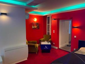 Cette chambre est dotée de murs rouges et de lumières vertes. dans l'établissement Hammam et spa privatifs by jordans collection, à Dijon