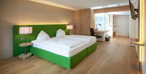 a large green bed in a room with a desk at Hotel Gasthof zur Post in Sankt Gilgen