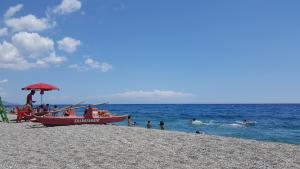 un barco en una playa con gente en el agua en B&B I Mastrazzi Riposto Giarre, en Riposto