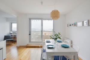 a white dining room with a white table and chairs at L'Opalin by Cocoonr - en plein cœur de Dinard in Dinard