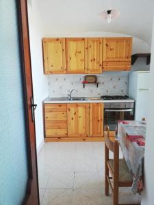 cocina con armarios de madera, fregadero y mesa en Casa Morgera, en Isquia