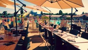 a row of tables and chairs with umbrellas and a pool at Mobile home 3 chambres 2 salles de bains dans camping 4 étoiles aux charmettes MH k168 in Les Mathes