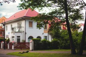 een wit huis met een rood dak bij Dom Gościnny Zielono Mi in Pobierowo
