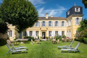 a large building with chairs and tables in the yard at La Baronnie Hôtel & Spa - Teritoria in Saint-Martin-de-Ré