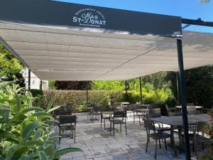 a patio with tables and chairs under a canopy at Le Mas Saint Donat in Sainte-Maxime