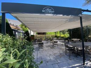 a patio with tables and chairs under a canopy at Le Mas Saint Donat in Sainte-Maxime