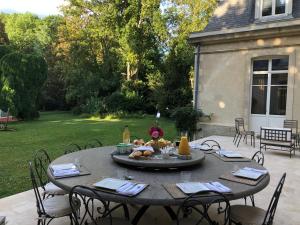 einen Terrassentisch mit Stühlen und einen Tisch mit Essen drauf in der Unterkunft Le Château d'Hermonville B&B / Chambres d'hôtes in Hermonville