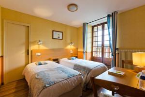 a hotel room with two beds and a table at Hôtel La Clairière in Chambon-sur-Dolore