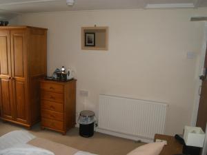 a bedroom with a bed and a dresser and a radiator at King's Arms in Lostwithiel