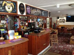 eine Bar in einem Pub mit einer Theke und Stühlen in der Unterkunft King's Arms in Lostwithiel