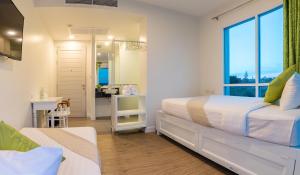 a white bedroom with a bed and a mirror at Chada@Nakhon in Nakhon Si Thammarat