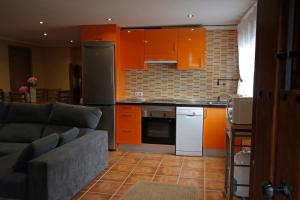 - une cuisine avec des armoires orange et un canapé dans la chambre dans l'établissement La casina de ribadesella 5 personas, à Ribadesella