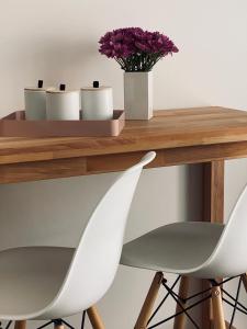 een houten tafel met twee witte stoelen en paarse bloemen bij Wanderlust Trier in Trier