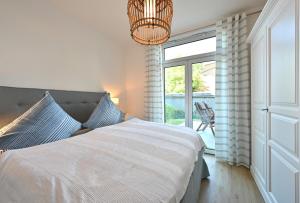 a bedroom with a bed and a window and a chandelier at Ferienwohnung TreibGood in Glowe