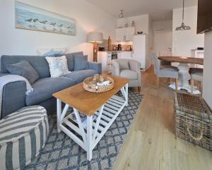 a living room with a blue couch and a table at Ferienwohnung TreibGood in Glowe +7 photos
