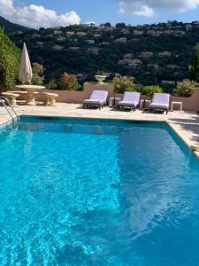 a large swimming pool with chairs and a table at Vue mer & piscine T2 climatisé à Cavalaire in Cavalaire-sur-Mer